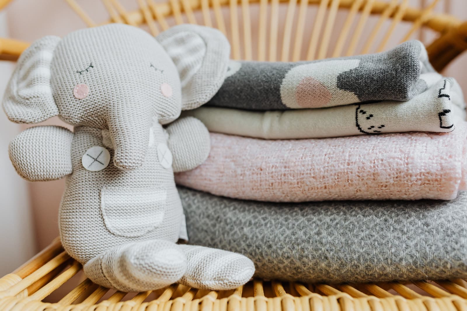 Knitted baby toys and folded blankets in a nursery basket